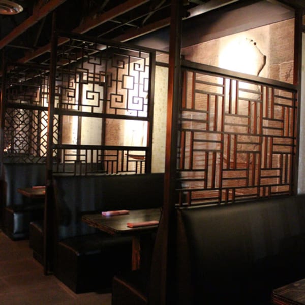 Aja Asian Cuisine & Lounge features dark wooden booths separated by decorative Asian-inspired screens.