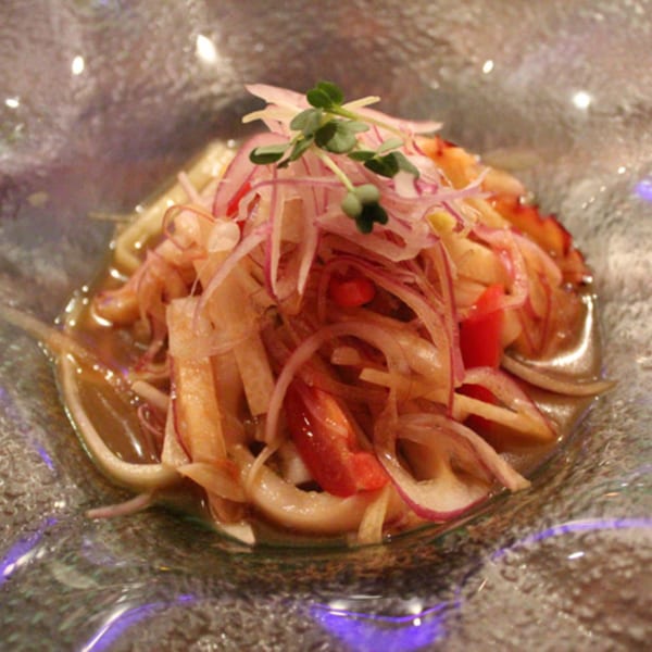 Asian dish with sliced red onions, red peppers, and sprouts in a clear bowl.