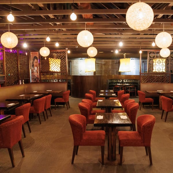Aja Asian Cuisine & Lounge dining room with red chairs, dark tables, and decorative lighting.