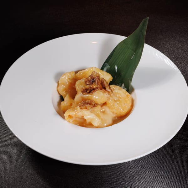 Aja Asian Cuisine's honey walnut shrimp, garnished with a green leaf, in a white bowl.