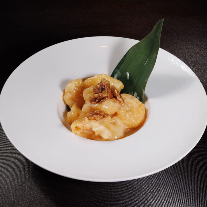 Aja Asian Cuisine's honey walnut shrimp, garnished with a green leaf, in a white bowl.