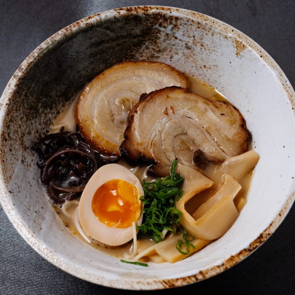 Aja Asian Cuisine's ramen bowl with pork, egg, bamboo shoots, and scallions in a rich broth.