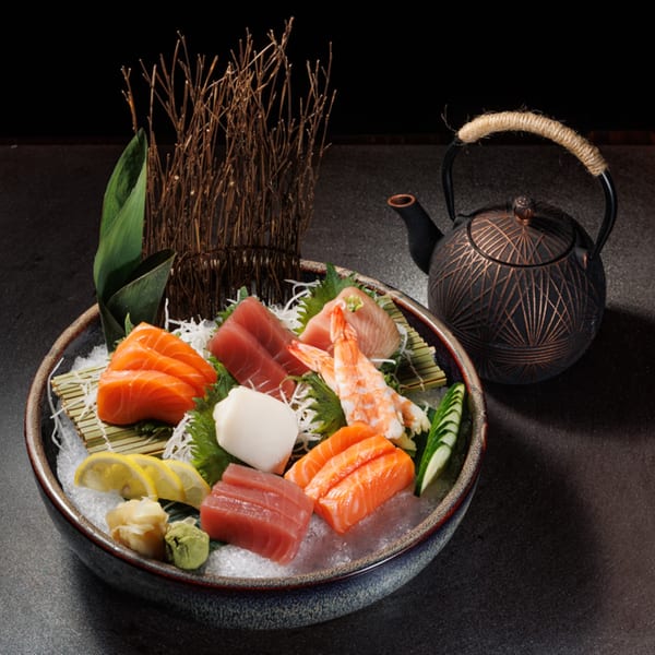 Aja Asian Cuisine's sashimi platter with salmon, tuna, shrimp, and scallops, served with a teapot.
