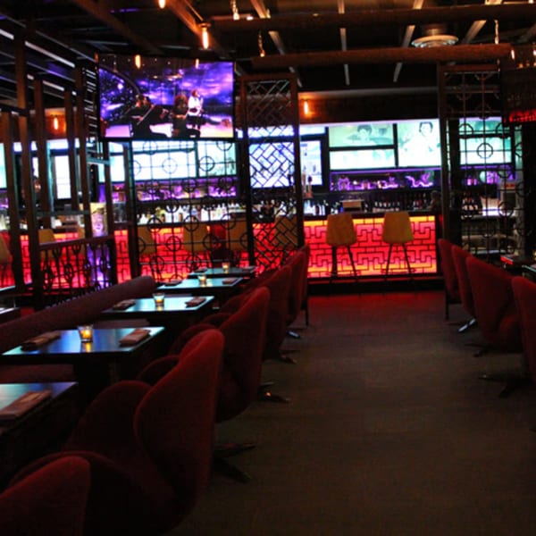 Aja Asian Cuisine & Lounge interior with red velvet chairs, dark tables, and a vibrant red lit bar.