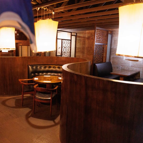 Aja Asian Cuisine & Lounge interior with curved wooden booths, tables, and glowing lanterns.