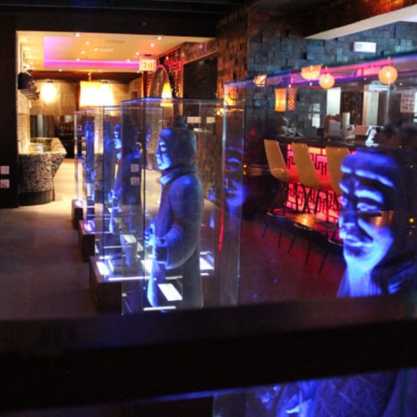 Aja Asian Cuisine & Lounge interior with blue-lit statues, a bar, and warm lighting.