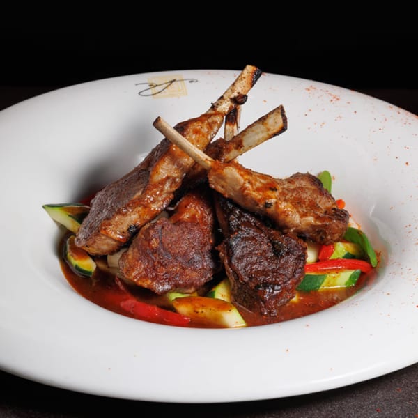 Aja Asian Cuisine's lamb chops with vegetables and sauce in a white bowl.
