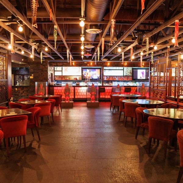 Aja Asian Cuisine & Lounge dining room with red chairs, round tables, and a red-lit bar.