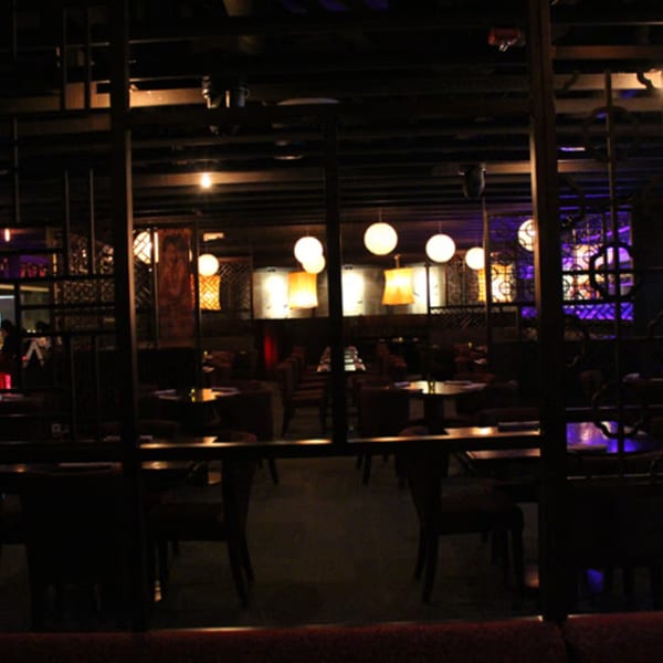 A dimly lit dining room at Aja Asian Cuisine & Lounge, featuring round and square hanging lights.