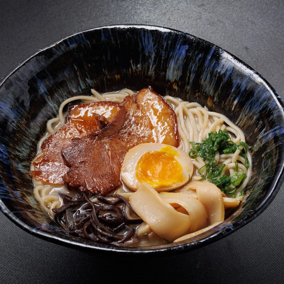 Aja Asian Cuisine's ramen bowl with pork belly, soft-boiled egg, noodles, and green onions.