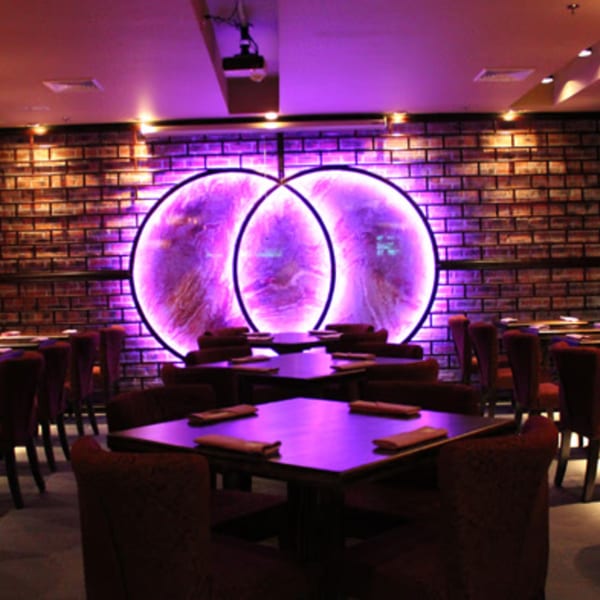 Aja Asian Cuisine & Lounge dining room with purple lighting, brick walls, and circular art.
